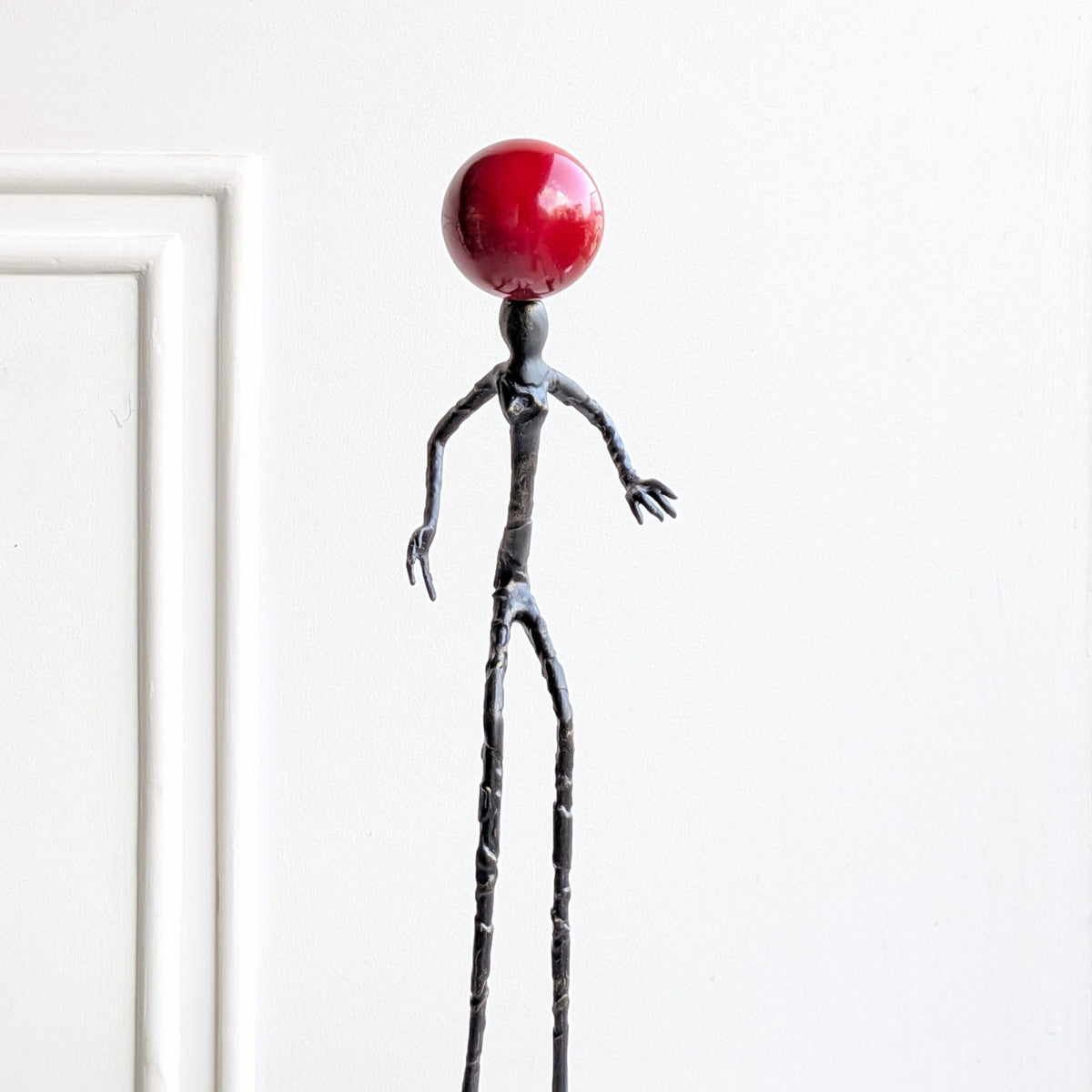Close detail of the glossy red orb and sculpted metal form of Redshift