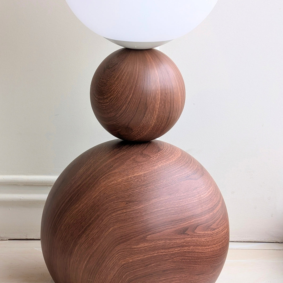 Close-up of the Solstice wood-grain stainless steel base and sculptural metal sphere