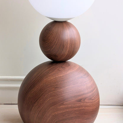 Close-up of the Solstice wood-grain stainless steel base and sculptural metal sphere
