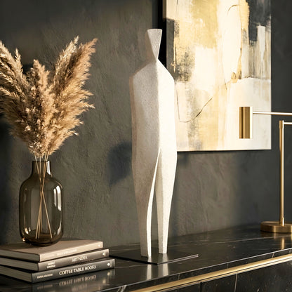 Stature textured resin and metal sculpture styled on a study console with abstract wall art