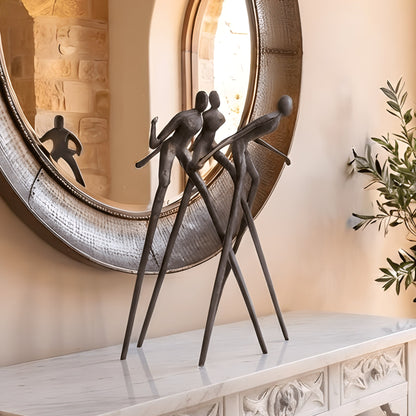 Synergy metal human figurine styled beneath a statement mirror in a luxury foyer