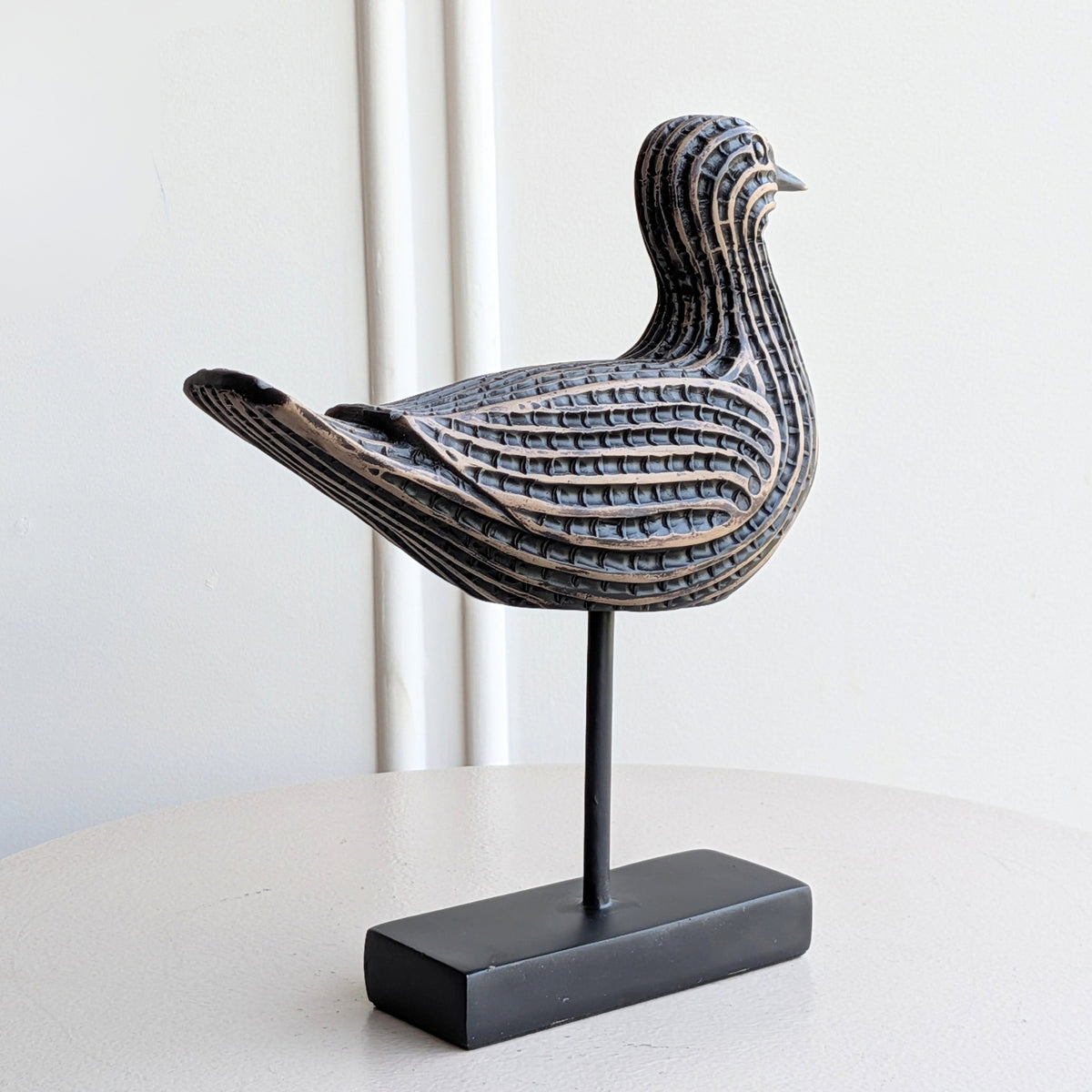Black resin bird sculpture on a metal stand for table decor